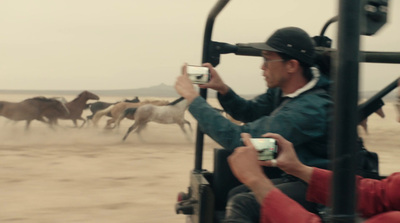 a man taking a picture of a herd of horses