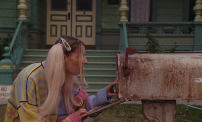 a woman with long blonde hair putting something in a mailbox