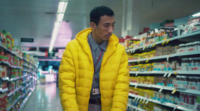 a man in a yellow jacket standing in a store aisle