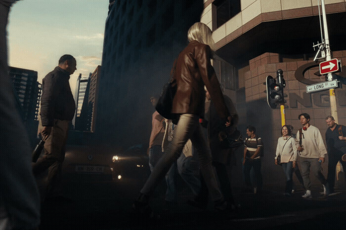 a group of people walking down a street next to a traffic light