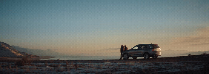 a couple of people standing next to a parked car