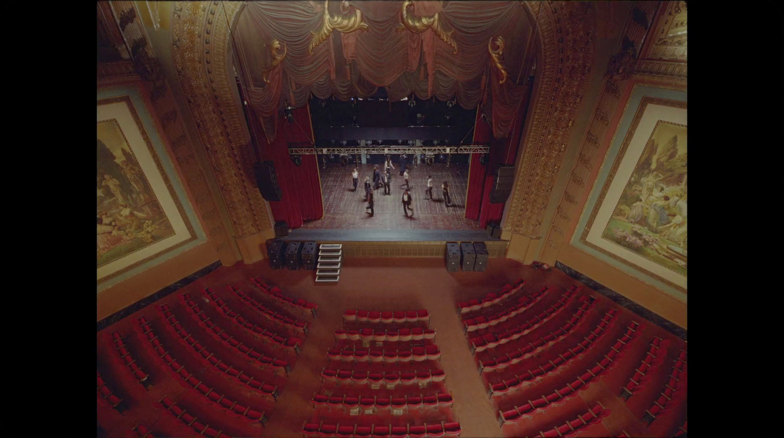 an empty theater with red seats and a ladder