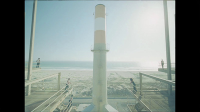 a tall white tower sitting on top of a sandy beach