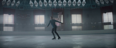 a man in a black suit skating on an ice rink