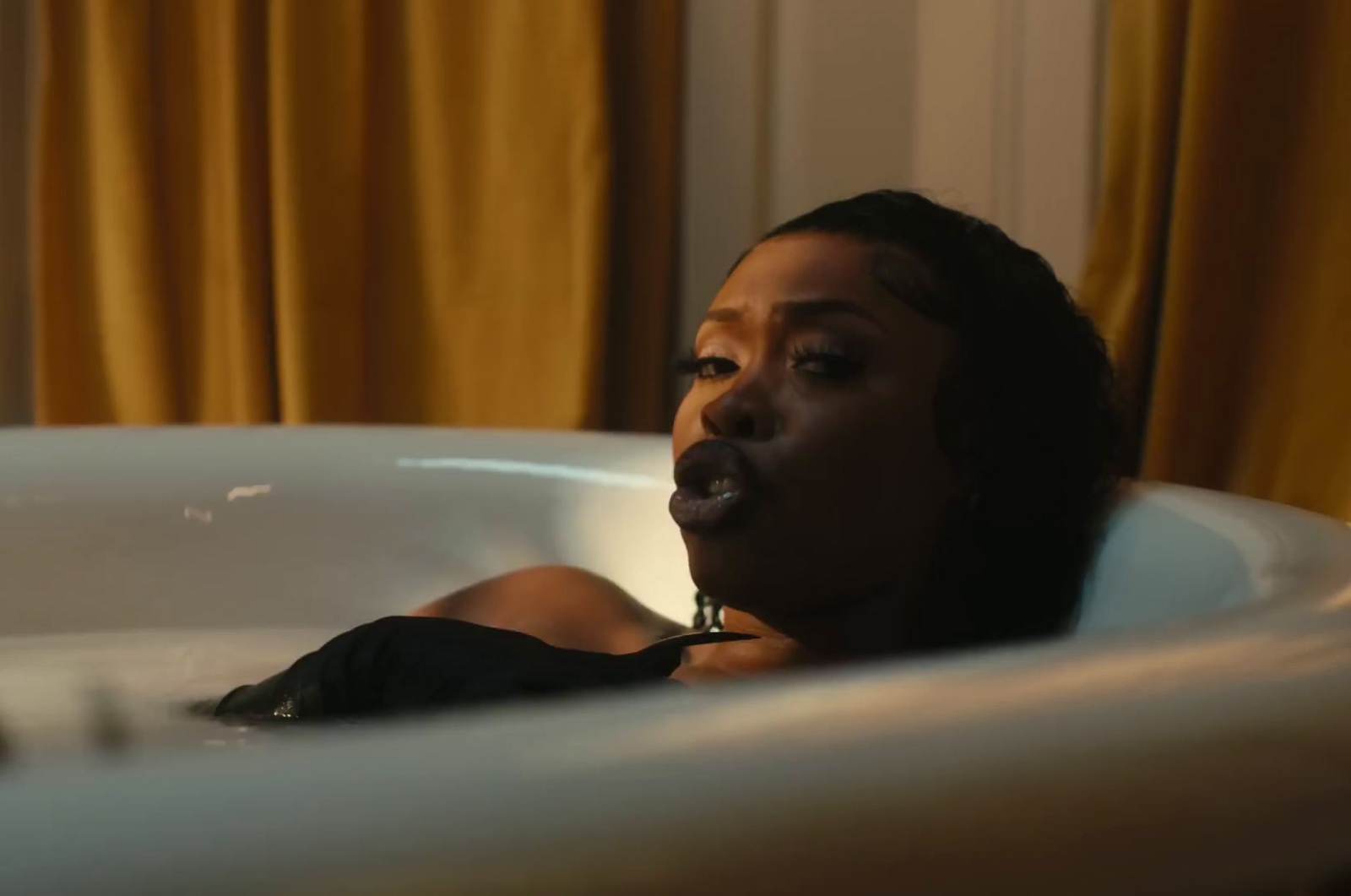 a woman laying in a bathtub with her mouth open