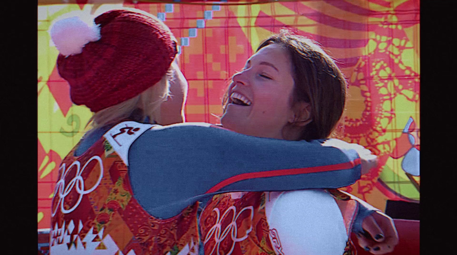 two women hugging each other in front of a colorful background