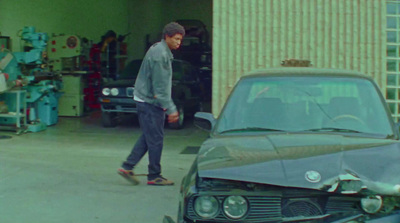 a man walking past a car in a garage