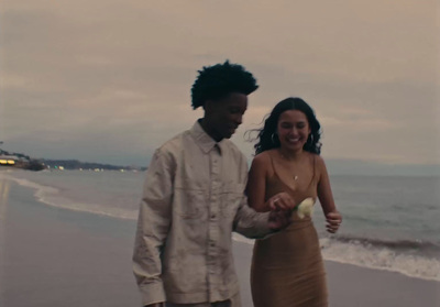 a man and woman standing on a beach next to the ocean