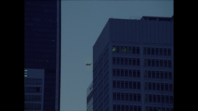 a plane flying in the sky over a tall building