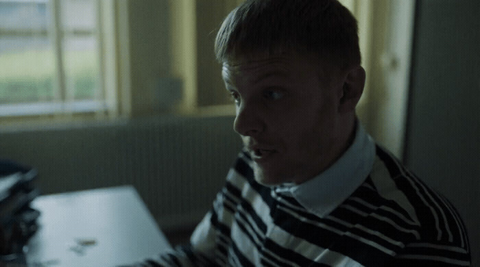 a man in striped shirt sitting at a desk