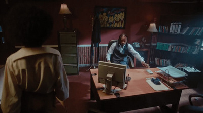 a man standing at a desk in front of a computer monitor