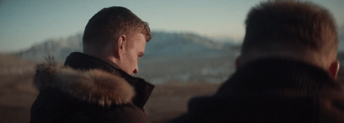 a man standing next to another man in a field