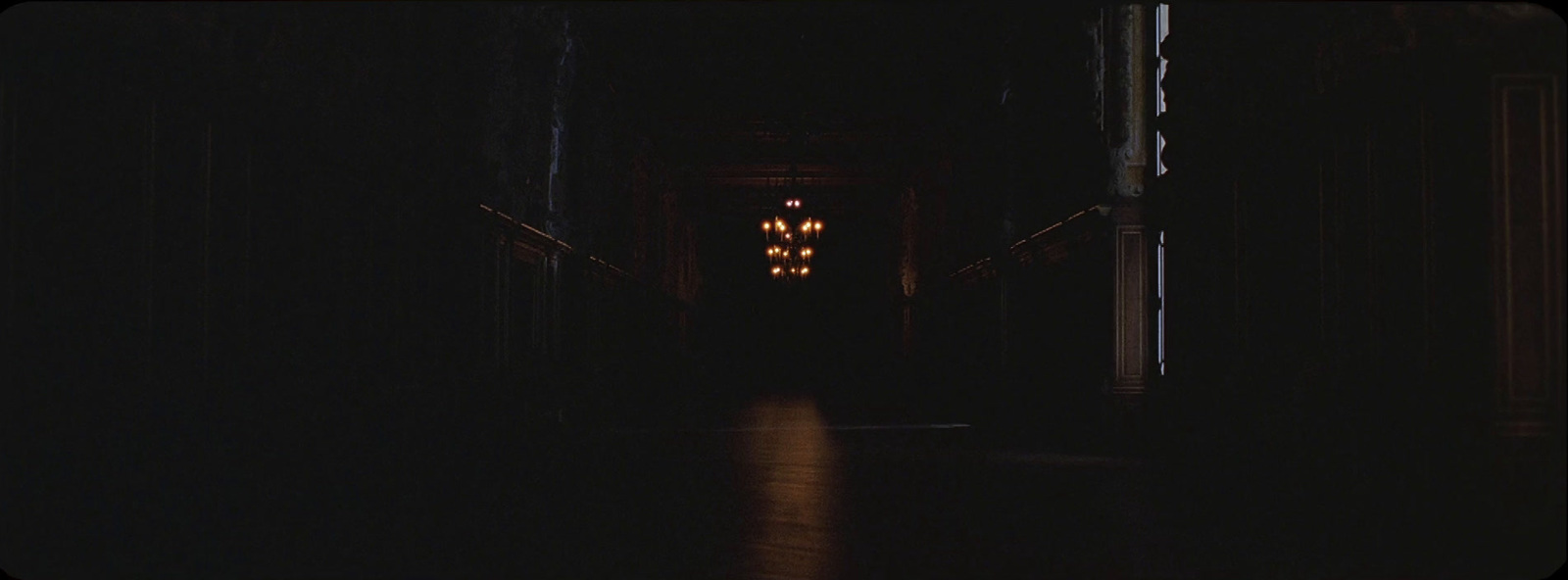 a dark hallway with a light at the end of it