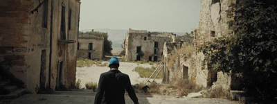 a man walking down a street with a blue hat on his head