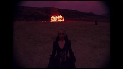 a woman standing in front of a burning house