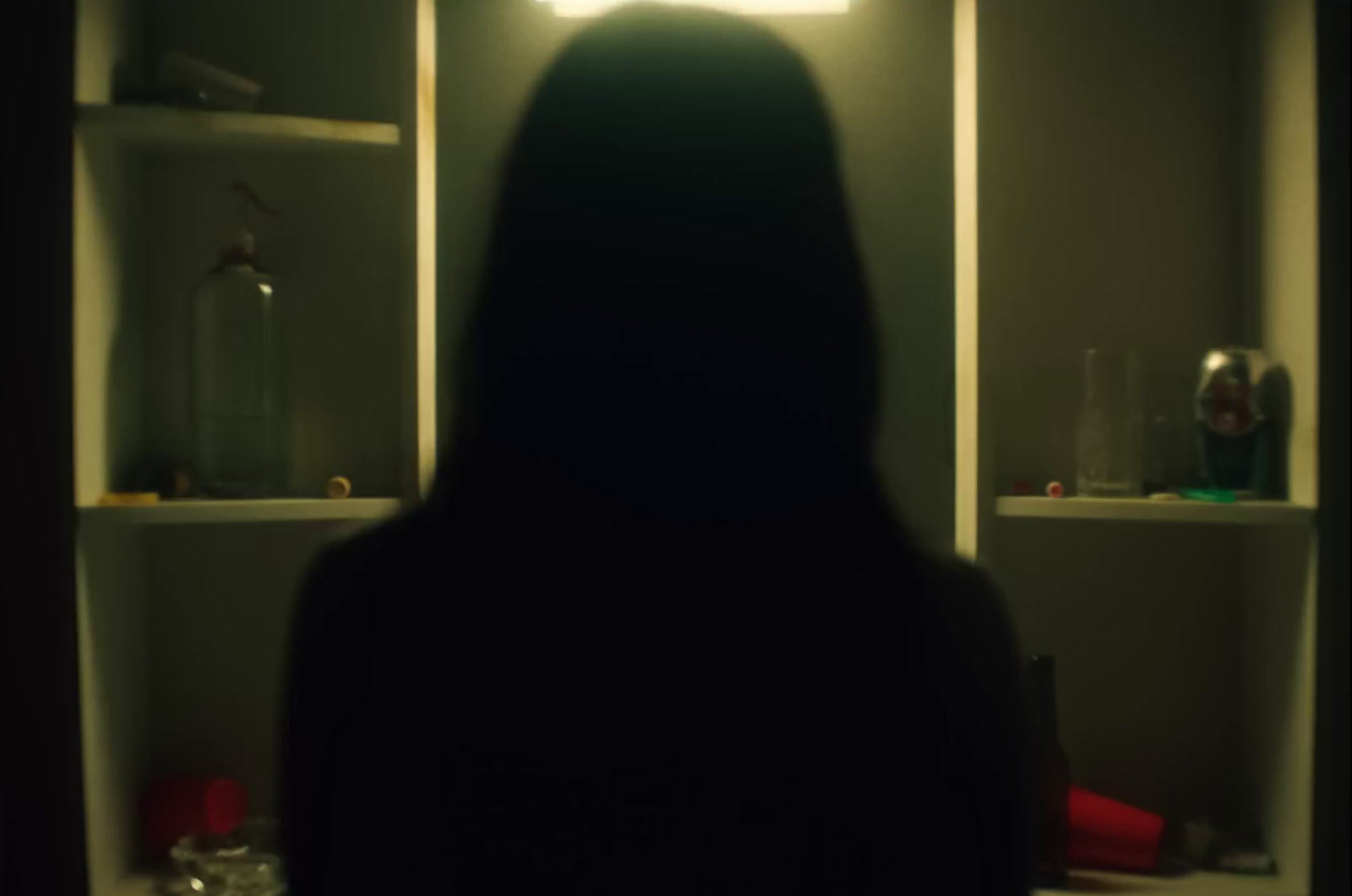 a woman standing in front of a mirror in a dark room