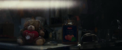 a teddy bear sitting on top of a counter next to a jar