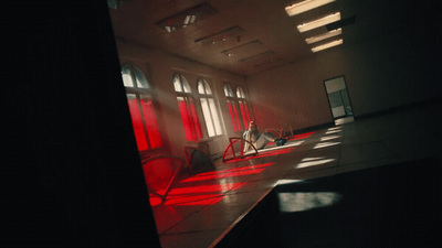 a person sitting in a room with red light coming through the windows