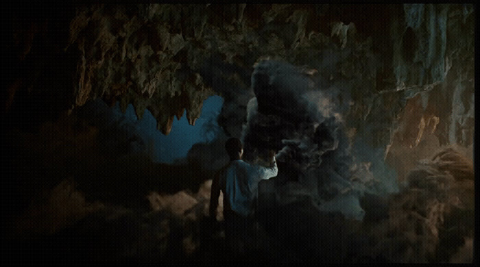 a man standing in front of a cave filled with smoke