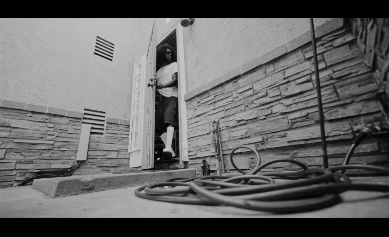 a black and white photo of a man opening a door