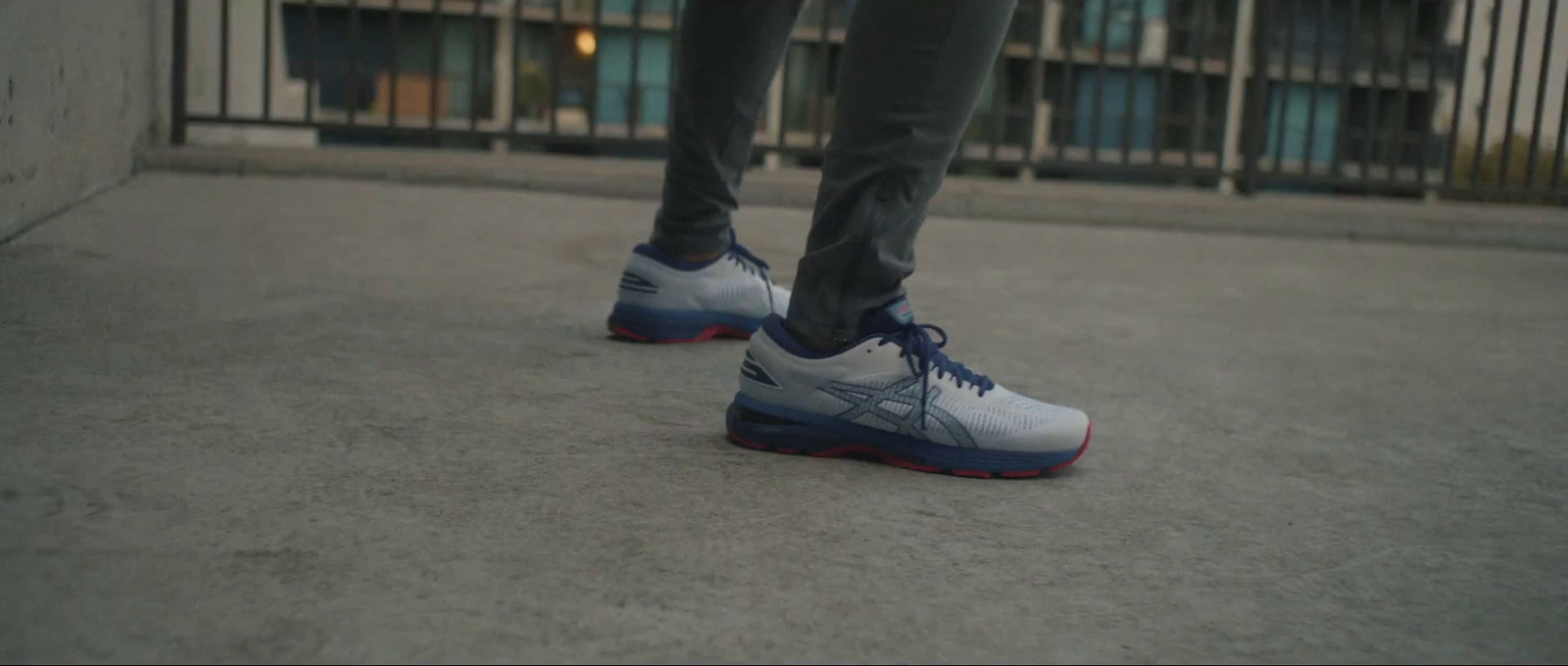 a person wearing blue and white shoes standing on a sidewalk