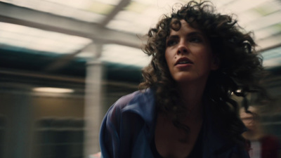 a woman with curly hair standing in a train station