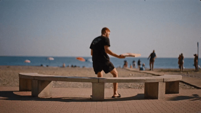 a man is playing frisbee on a bench near the beach