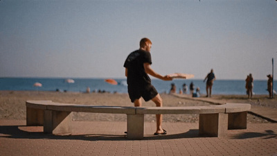 a man is playing frisbee on a bench near the beach