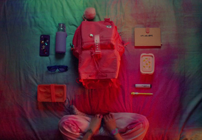 a person sitting on a bed with a backpack and other items