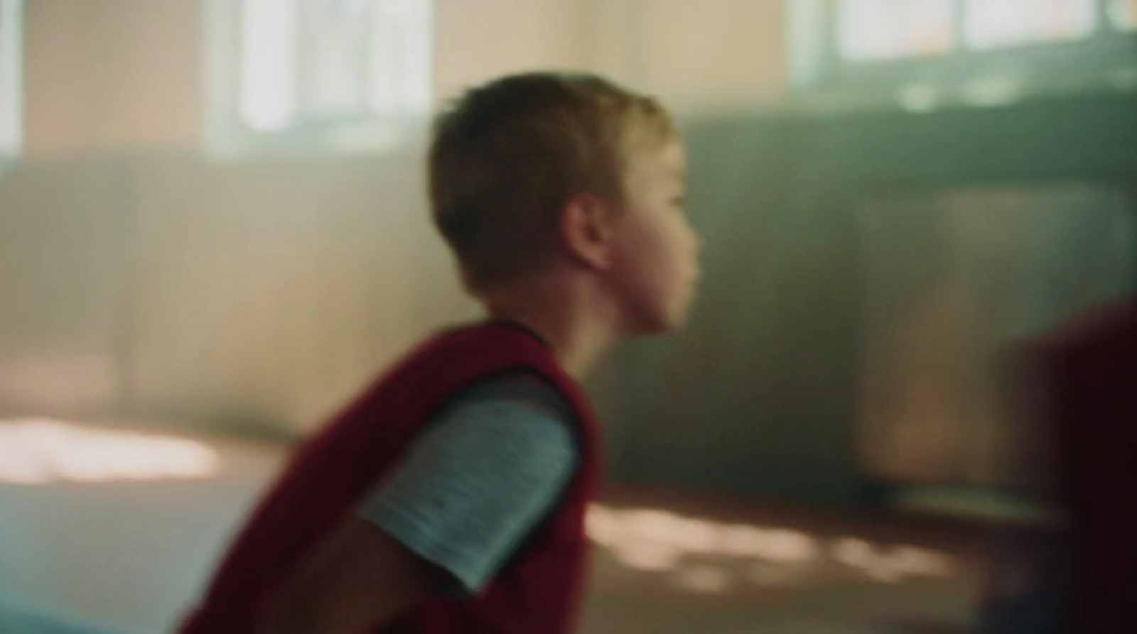 a young boy in a red vest standing in a room