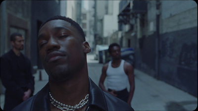 a man in a black leather jacket standing on a city street