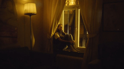 a man sitting on a window sill looking out the window