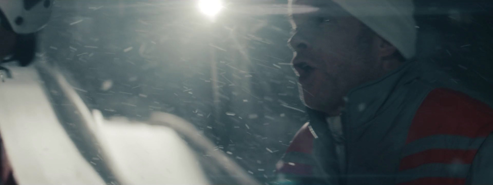 a man in a red and white jacket looking out a window