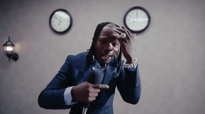 a man holding a microphone in front of two clocks