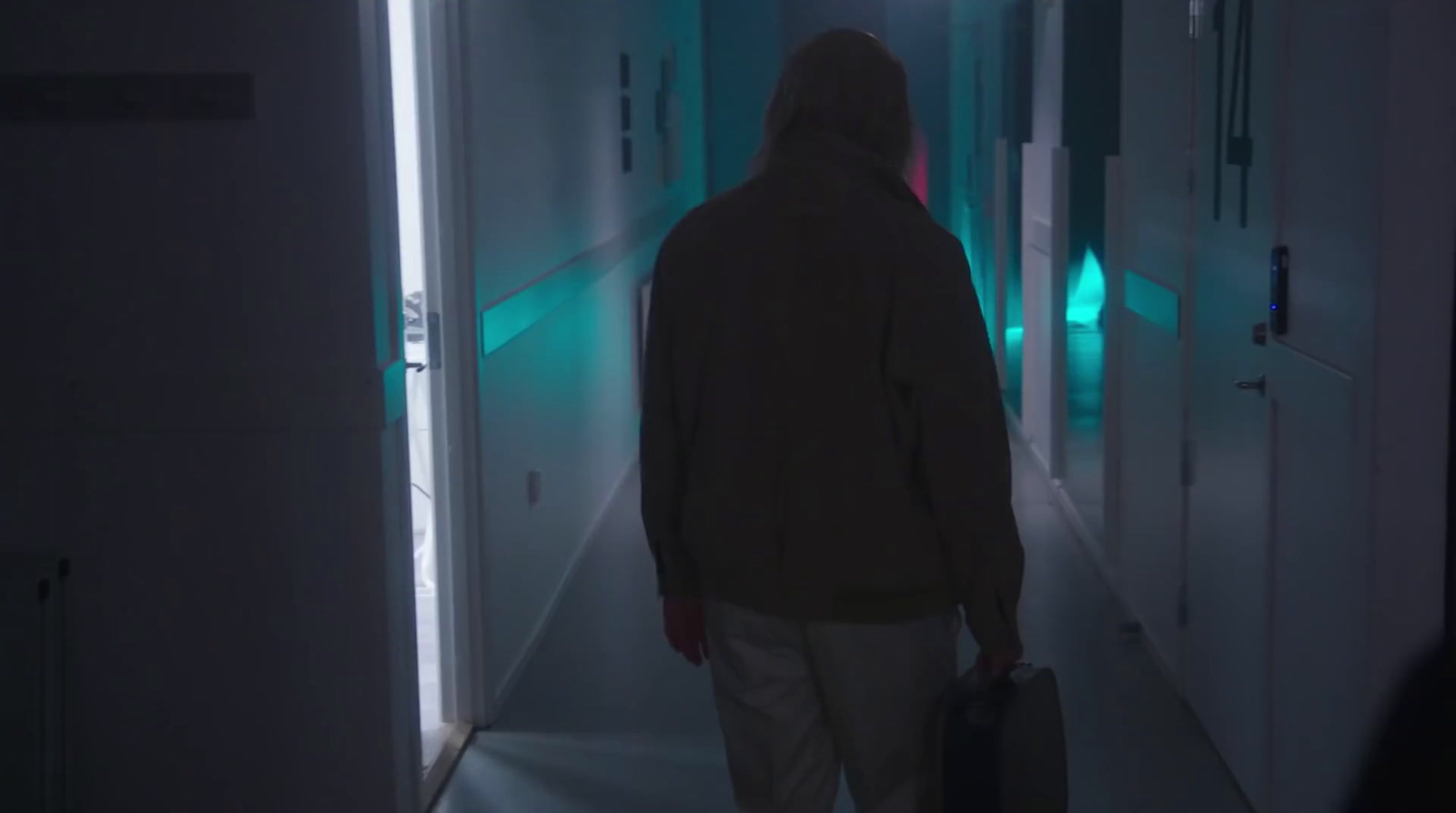 a man with a suitcase walking down a hallway