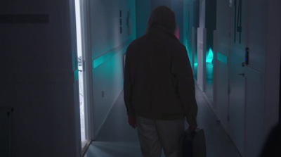 a man with a suitcase walking down a hallway