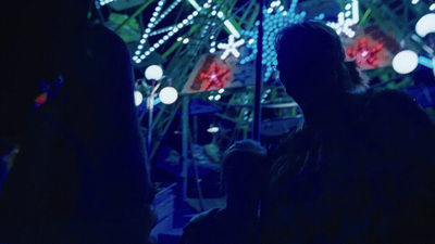 a person standing in front of a ferris wheel at night