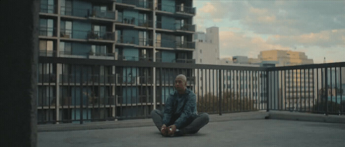 a man sitting on the ground in front of a building