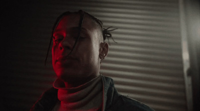 a man with dreadlocks standing in a dark room