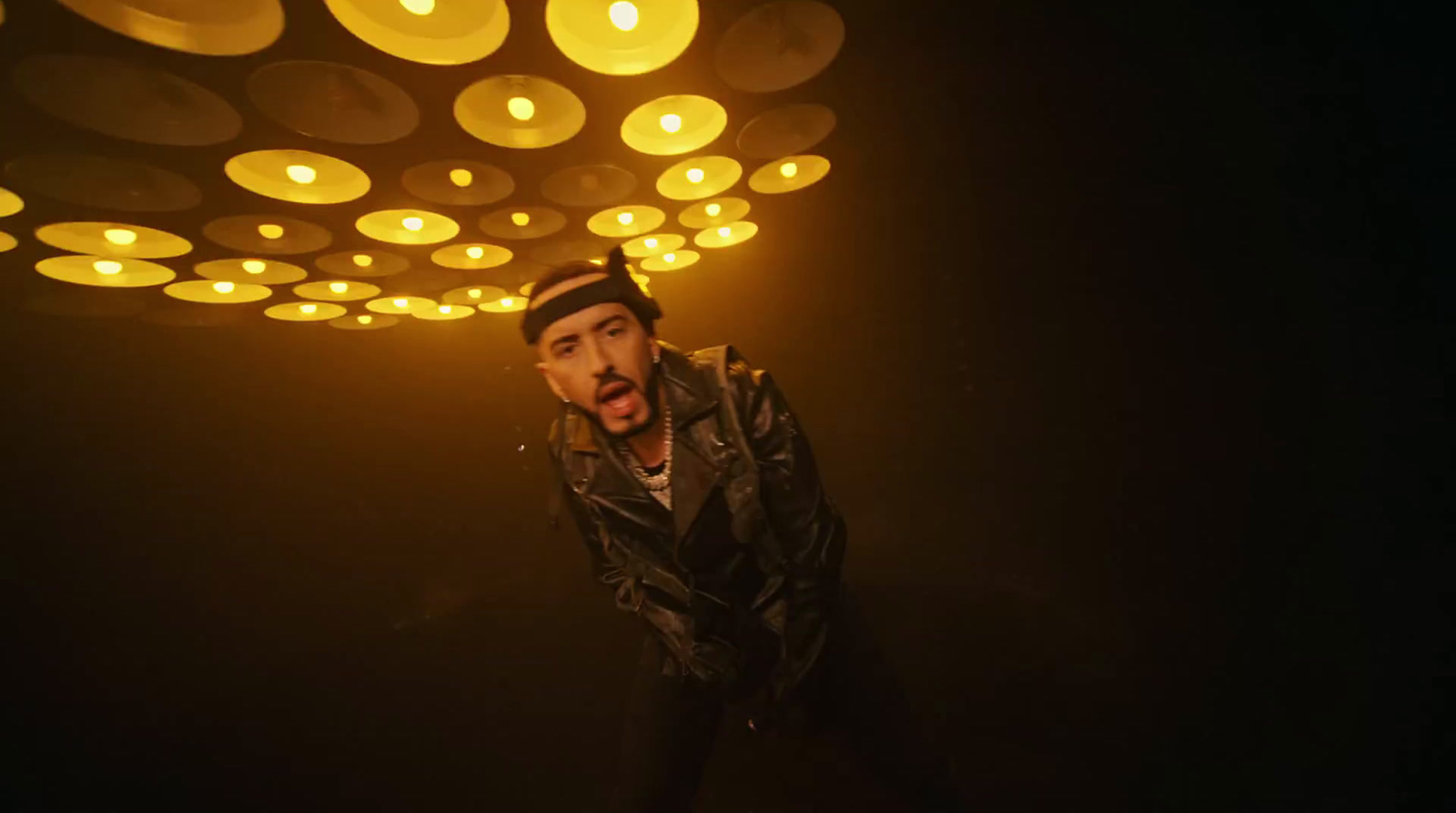 a man in a leather jacket standing in a dark room