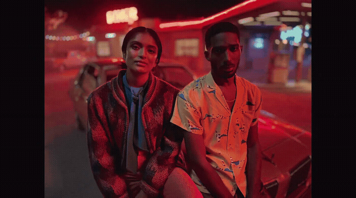 two young men sitting on the hood of a car