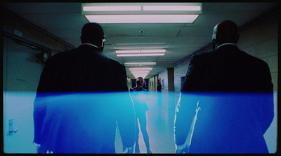 two men in suits walking down a hallway