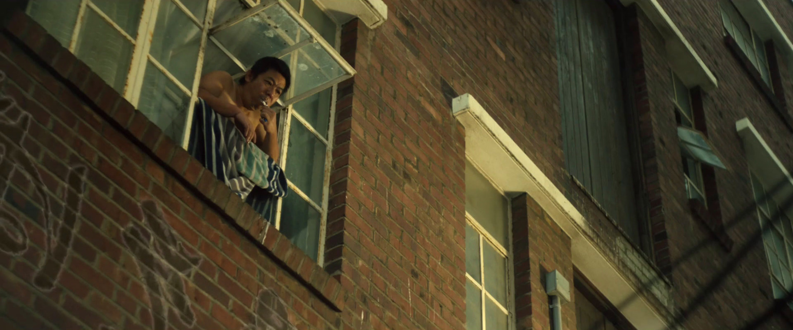 a man standing in a window of a brick building