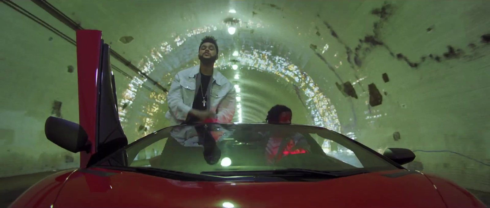 a man standing next to a red car in a tunnel