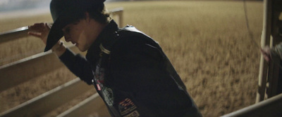 a man in a cowboy hat leaning against a fence