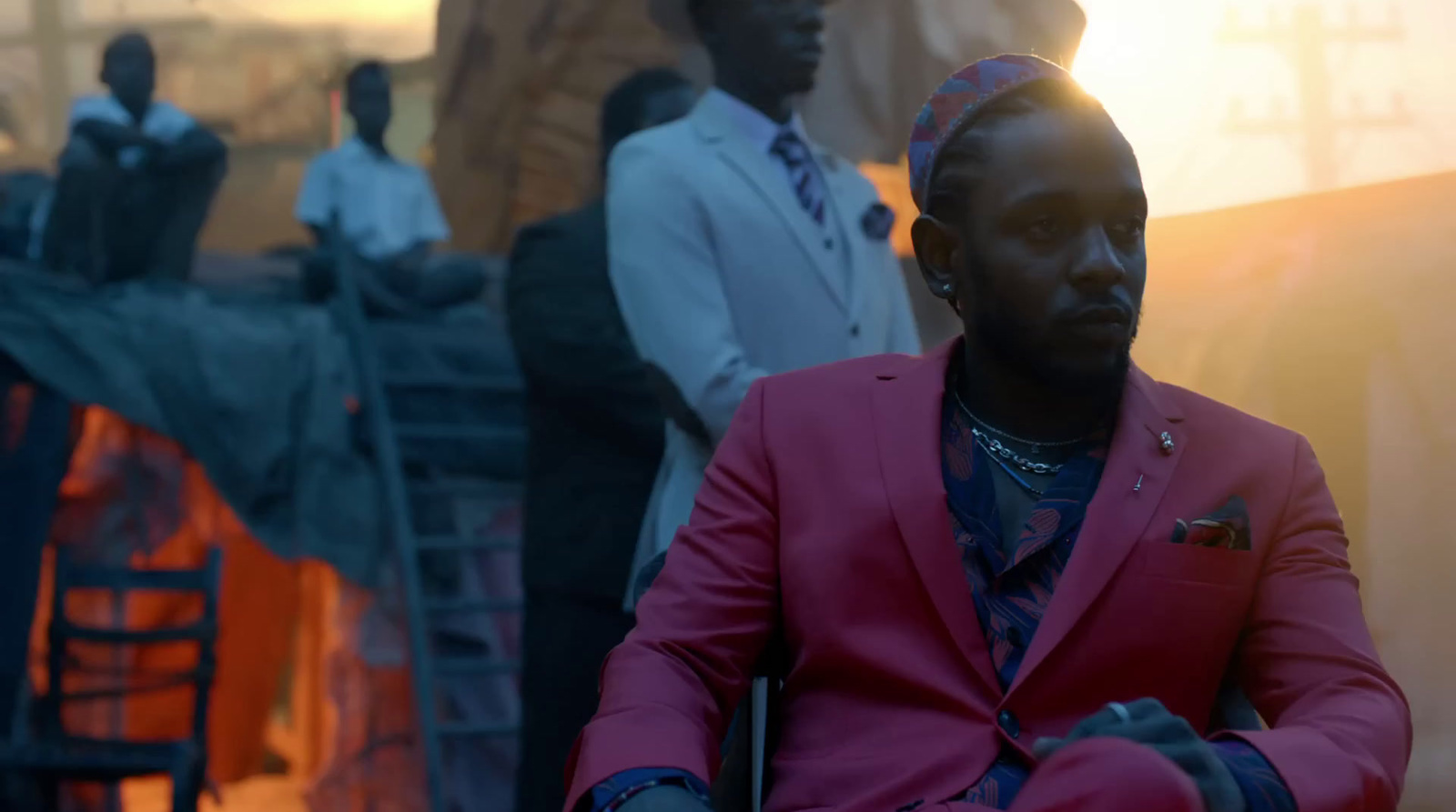 a man in a pink suit sitting in a chair