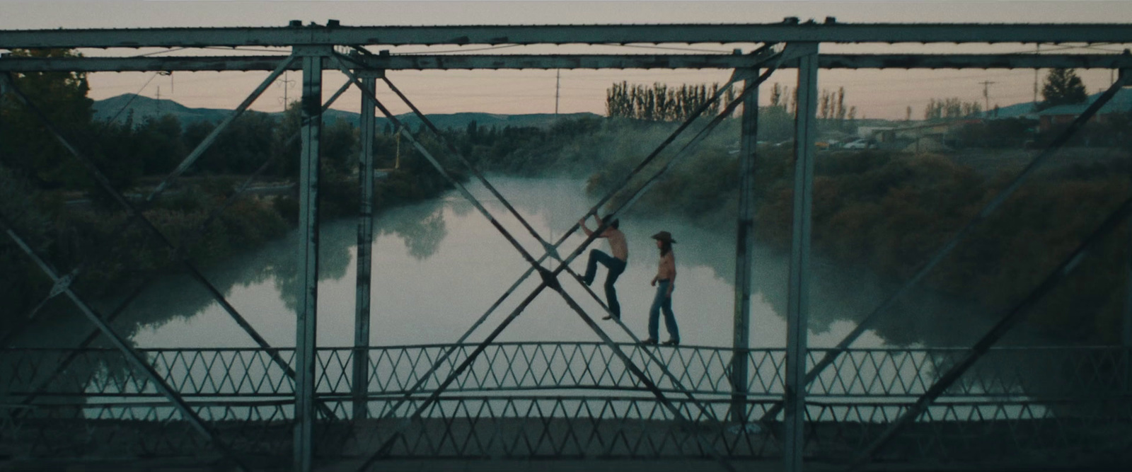 two people crossing a bridge over a river