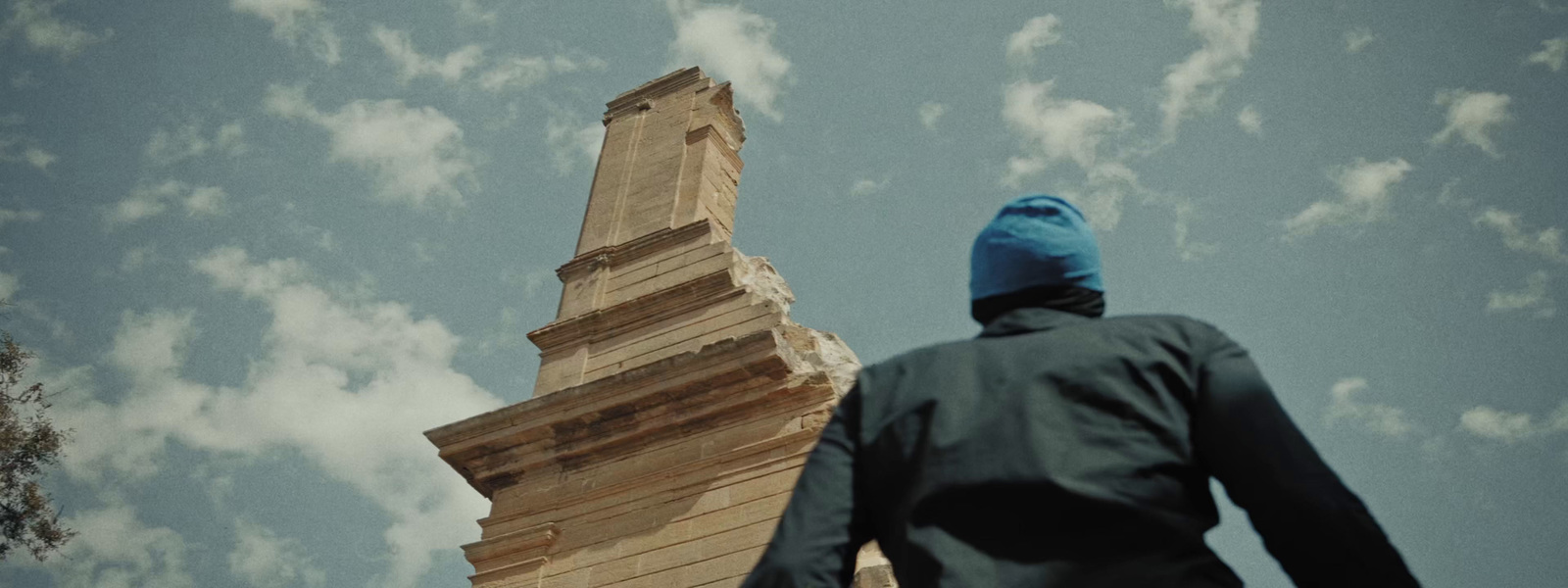 a man in a blue hat is looking up at a tall tower