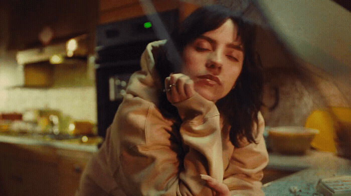 a woman sitting in a kitchen talking on a cell phone