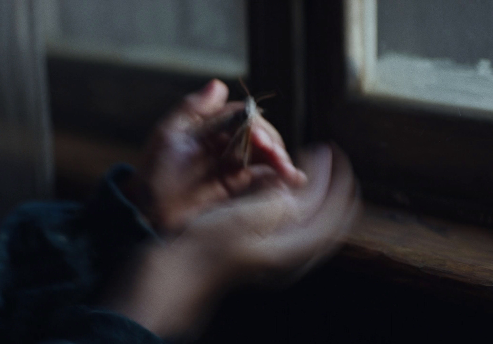 a person holding something in their hand near a window